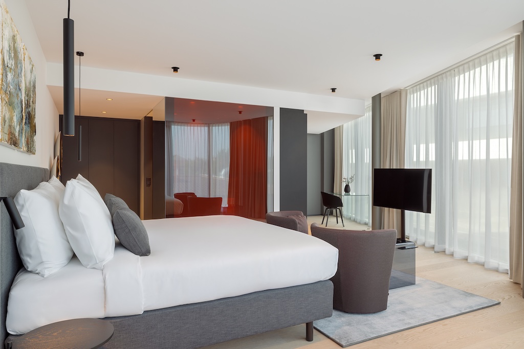 Großzügiges Hotelzimmer mit bodentiefen Fenstern, Designmöbeln und komfortablem Doppelbett