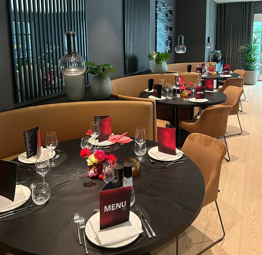 Stilvolles Hotelrestaurant mit runden, gedeckten Tischen und moderner Innenarchitektur