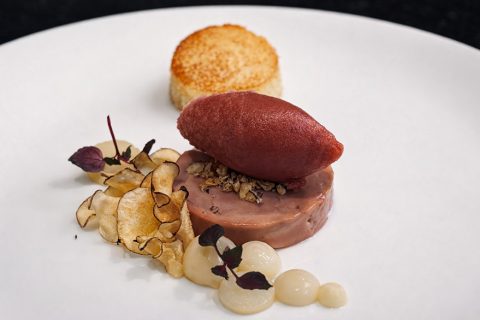 Runde Terrine mit rotem Sorbet, Chips und Sauce auf weißem Teller