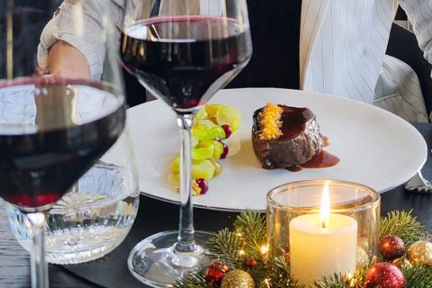 Rinderfilet liegt auf Teller, daneben Kerze und Rotweingläser auf Tisch