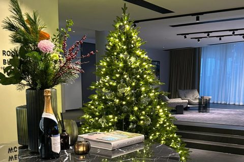 Weihnachtsbaum leuchtet neben Tisch mit Blumen in moderner Lobby