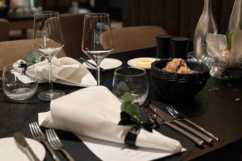 Esstisch gedeckt mit Gläsern, Servietten und Brotkorb im Restaurant