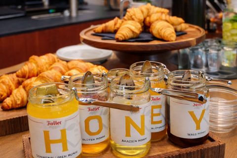 Gläser mit 'HONEY' (Blütenhonig, Akazienhonig, Waldhonig) vor Croissants