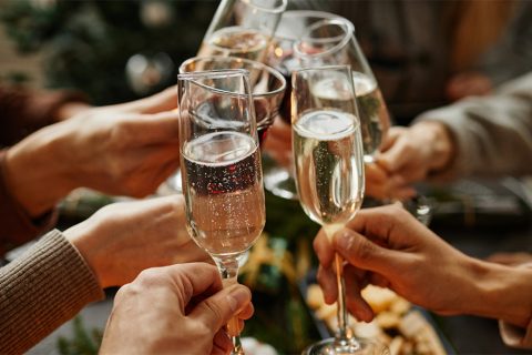 Sektgläser stoßen an, Hände über festlich gedecktem Tisch