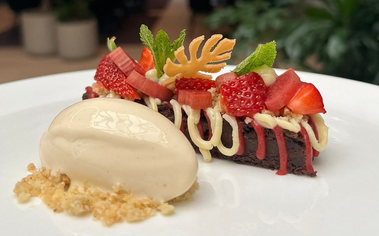 Schokoladentarte, garniert mit Erdbeeren und Vanilleeis auf weißem Teller