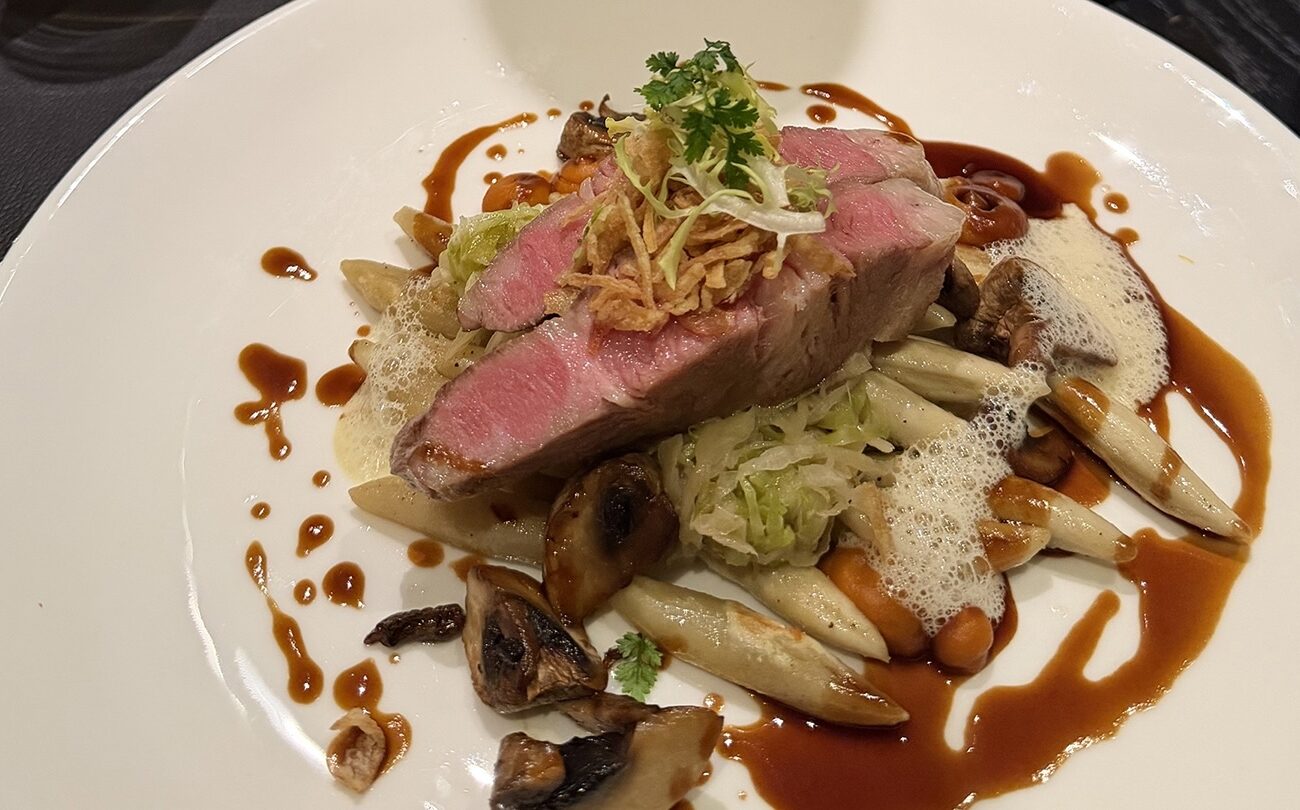 Rosa gebratenes Steak, serviert auf Spargel und Pilzen mit Sauce