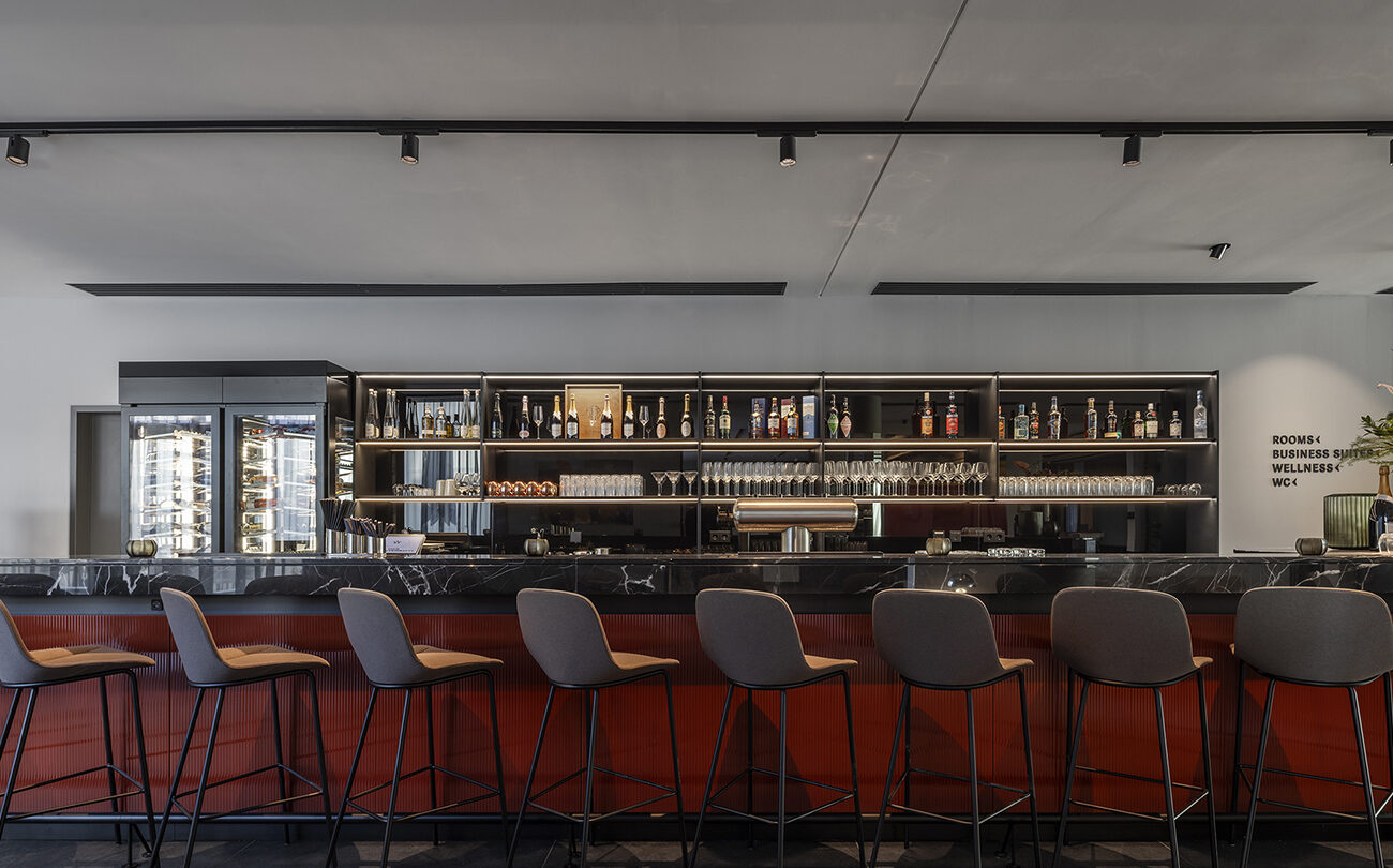Bar nahe Stuttgart mit Hockern, Regal dahinter; Wandtext: ROOMS BUSINESS SUITE WELLNESS WC