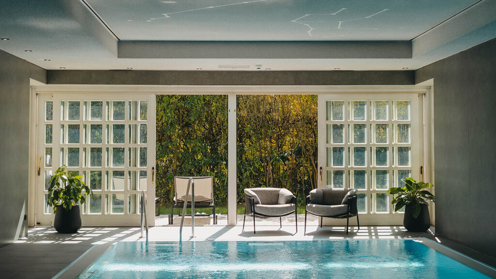 Innenpool im Hotel nahe Stuttgart liegt ruhig und spiegelt Sonnenlicht, vor großen Schiebetüren zum Garten