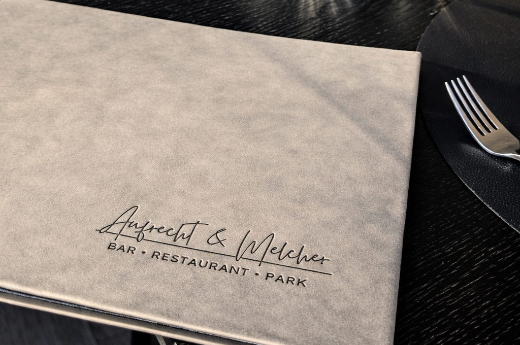 Menü mit Aufschrift 'Aufrecht & Melcher BAR · RESTAURANT · PARK' auf Tisch